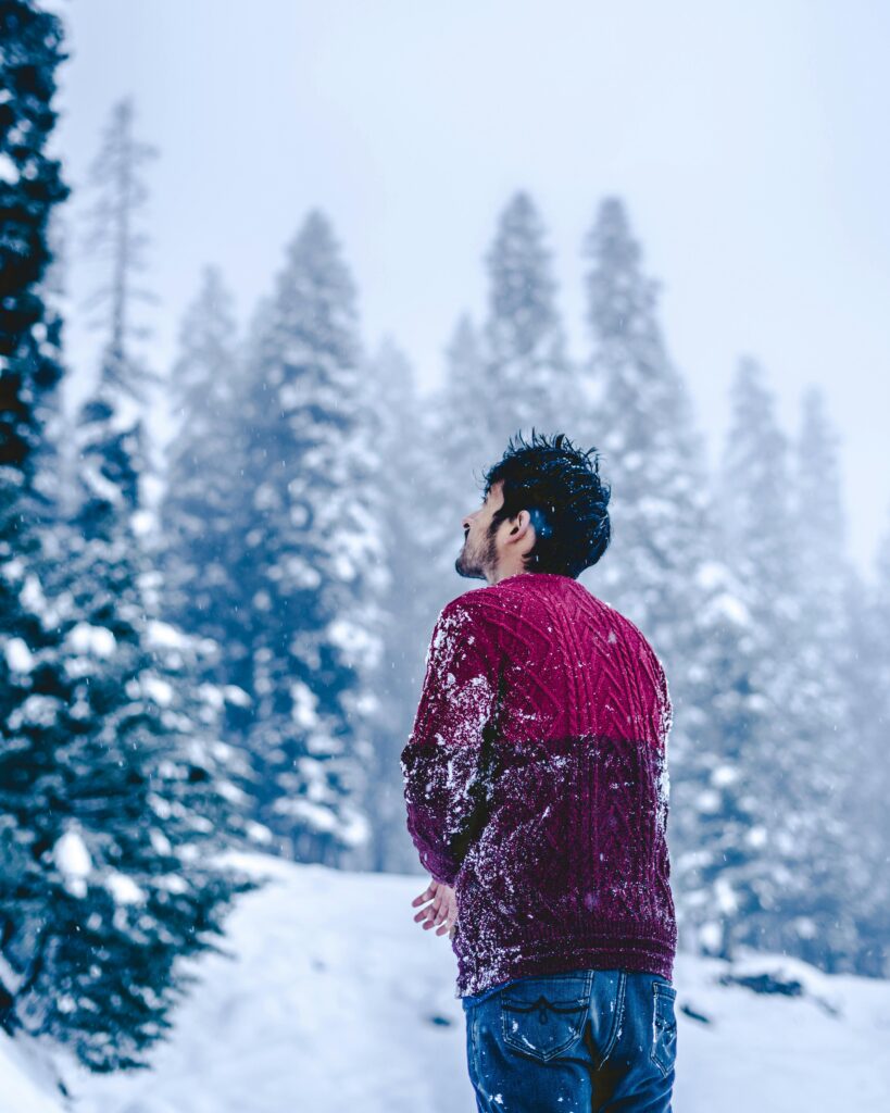 Man in a snowy forest in Shopian, absorbed in the serene winter landscape.